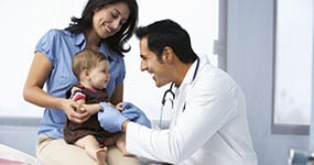 Happy Child in mother lap while Doctor examining child